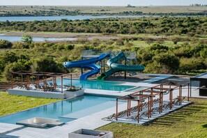 Zona de piscina con toboganes, sillones de descanso y vistas del paisaje circundante.