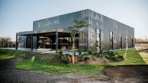 A modern building with a flat roof, large windows, and a covered outdoor area.