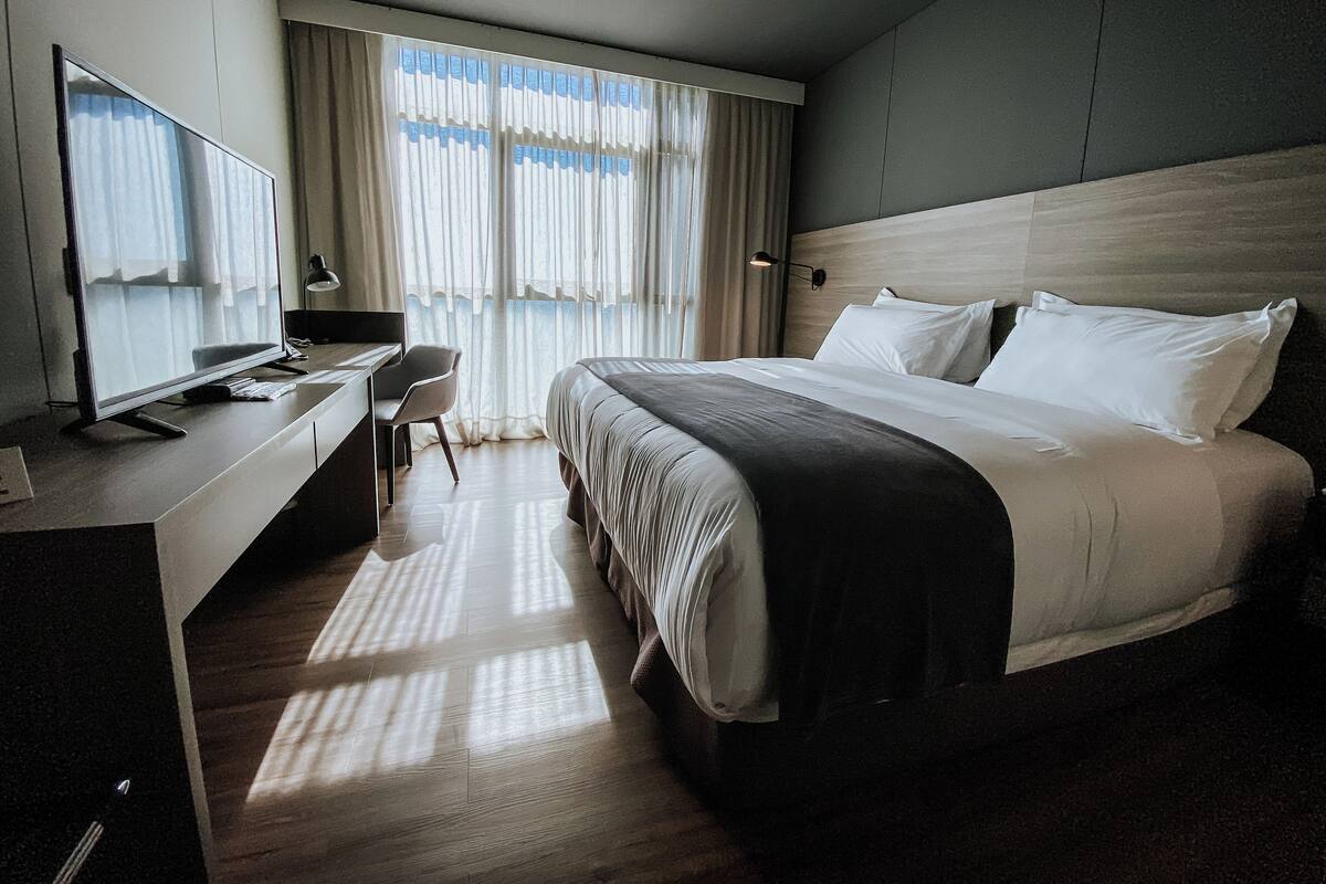 Une chambre d’hôtel moderne avec un grand lit, un bureau équipé d’un ordinateur et une chaise.