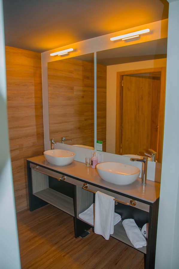 Un baño moderno con dos lavamanos, un espejo grande y paredes de madera.