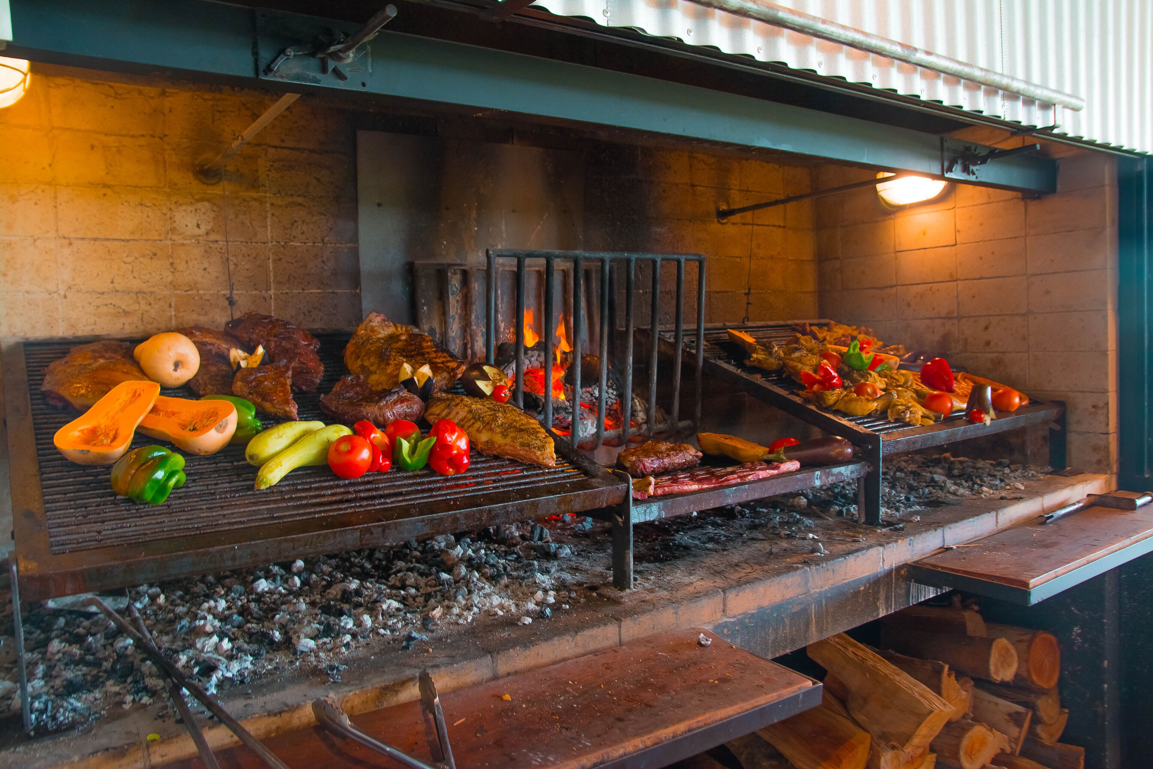 A grill with various meats and vegetables being cooked.