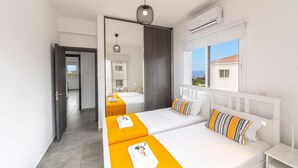 Habitación de hotel con dos camas, un espejo grande, aire acondicionado y vista al exterior.