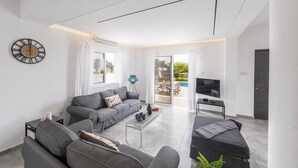 Una sala moderna con un sofá gris, una mesa de centro y un televisor.