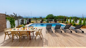 A rooftop pool area with a dining table and chairs, a pool, and a view of the sea. - Napa Bay View Villa 4 (Ayia Napa)