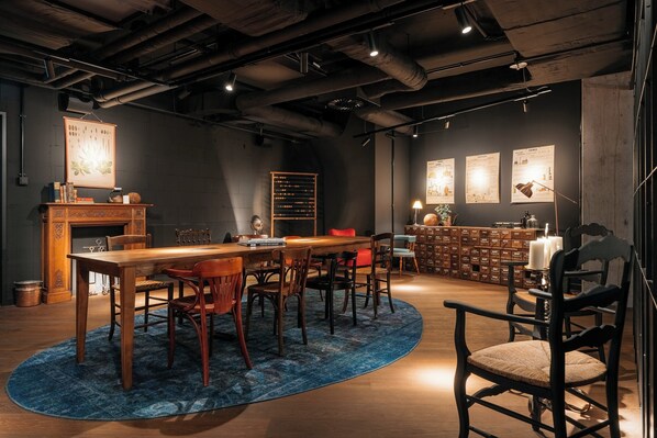 Une salle de conférence avec une table en bois, des chaises, un tapis bleu, une cheminée et une bibliothèque.
