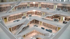 A multi-level library with bookshelves, seating areas, and staircases. - Ruby Hanna Hotel Stuttgart by IHG (Stuttgart)