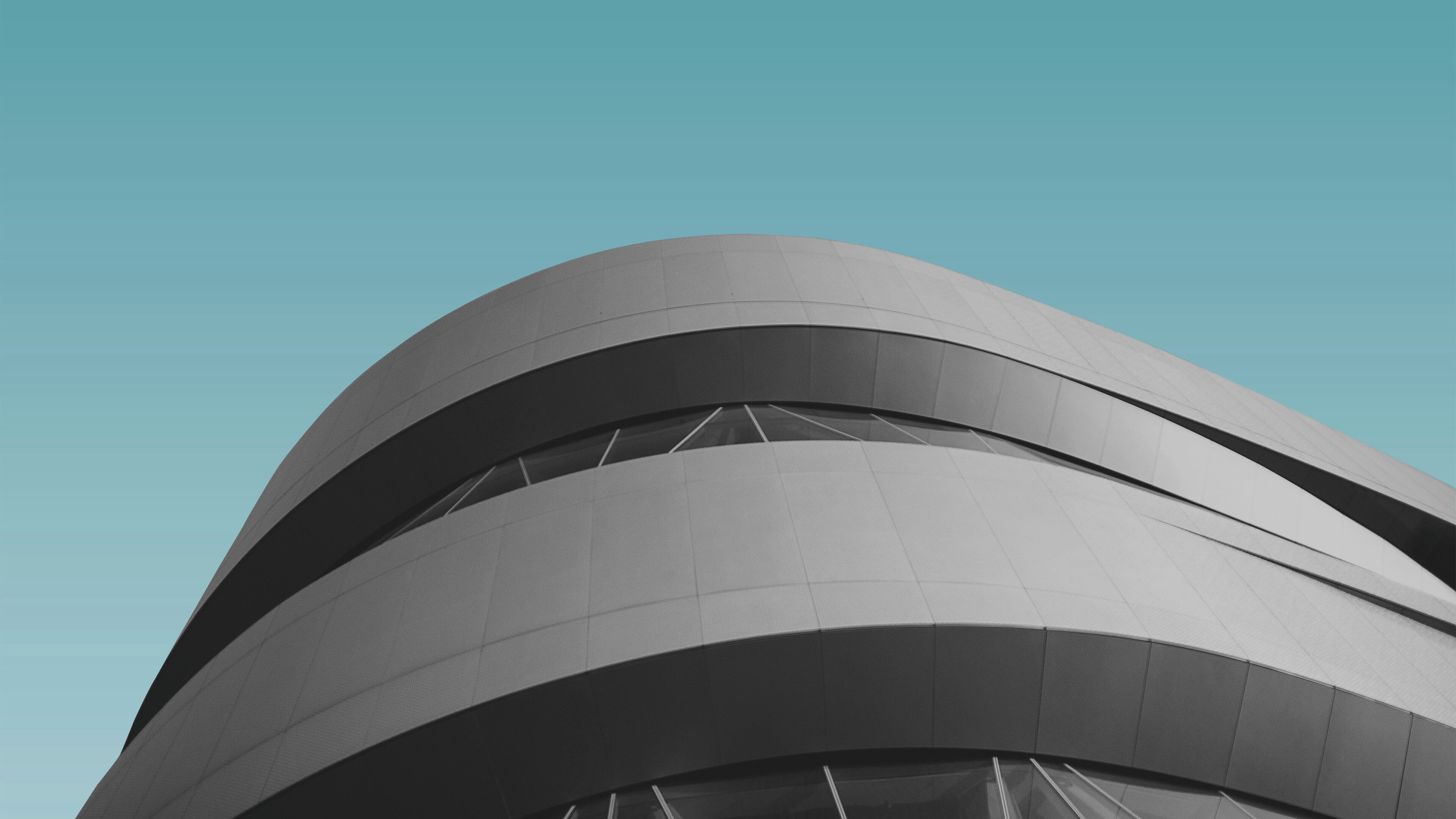 A modern architectural structure with curved lines and a series of windows.