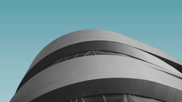 A modern architectural structure with curved lines and a series of windows.