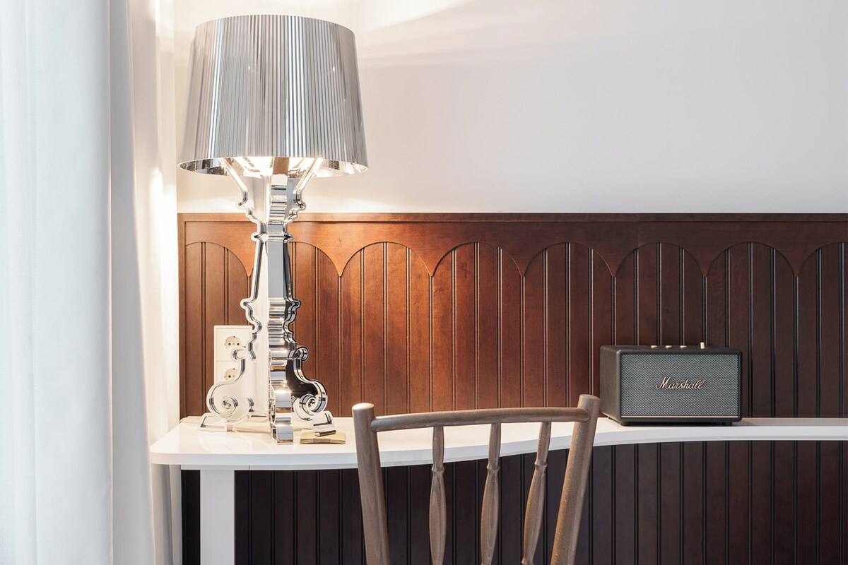 Una mesa con una lámpara, una radio y una silla en una habitación con paneles de madera.