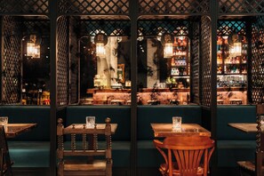 Un restaurante con cabinas, mesas de madera y luces colgantes.