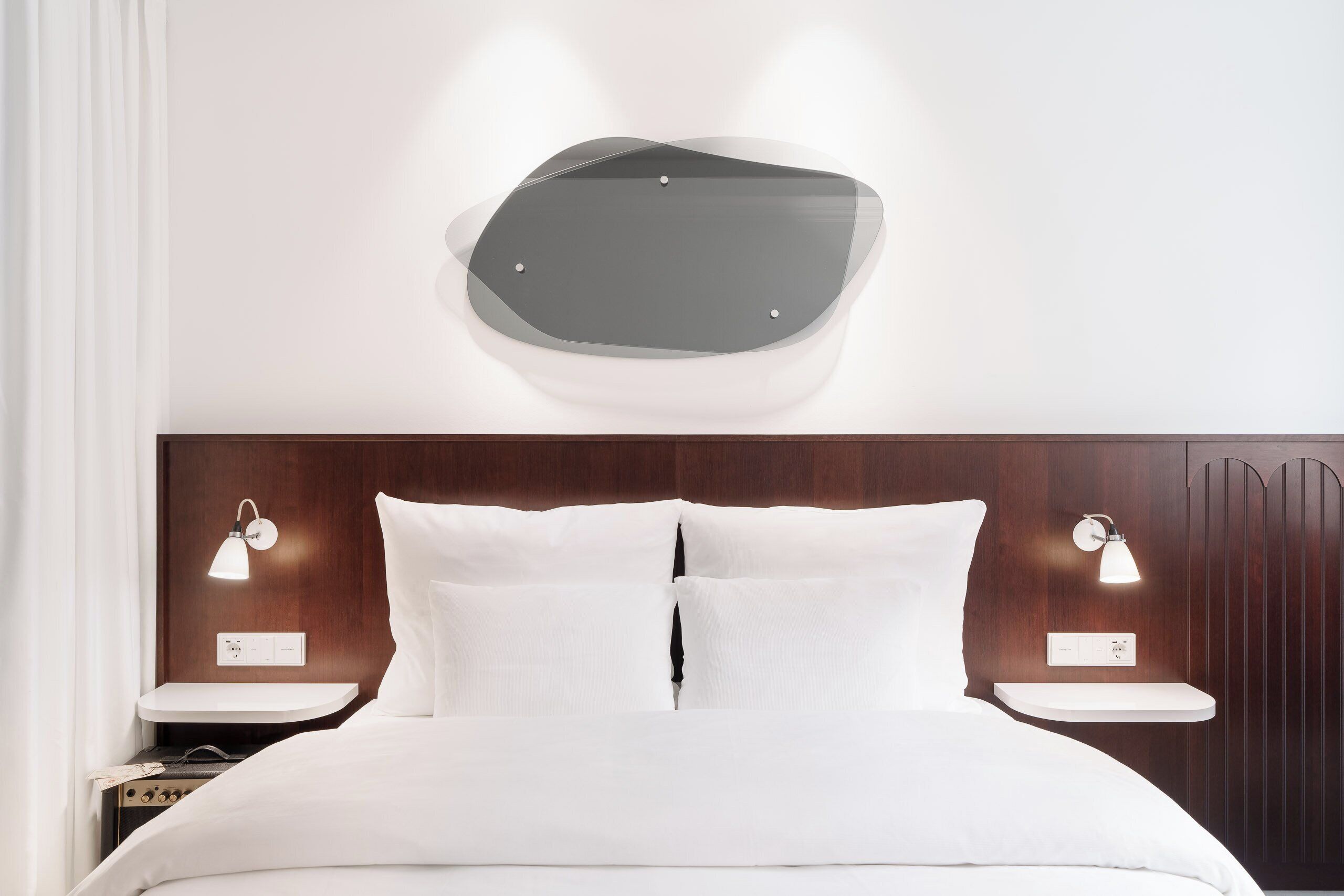 Una habitación de hotel moderna con una cama grande, mesitas de noche e iluminación empotrada en la pared.
