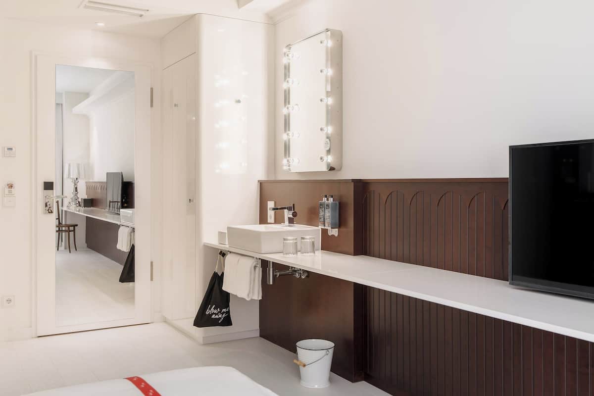 Un baño moderno con tocador, espejo y televisor.