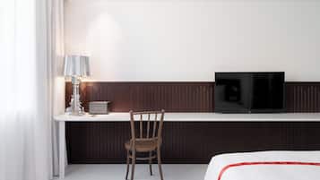 Ett hotellrum med en säng, ett skrivbord med en tv, en stol och en lampa.