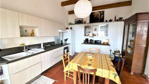 Kompakti keittiö, jossa on ruokailutila, puupalkit, riippuvalaisin ja laattalattia.