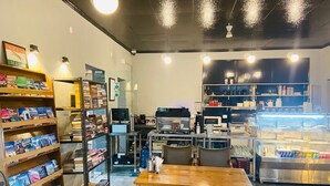 Una librería con estanterías llenas de libros, una máquina de café y una vitrina con artículos.