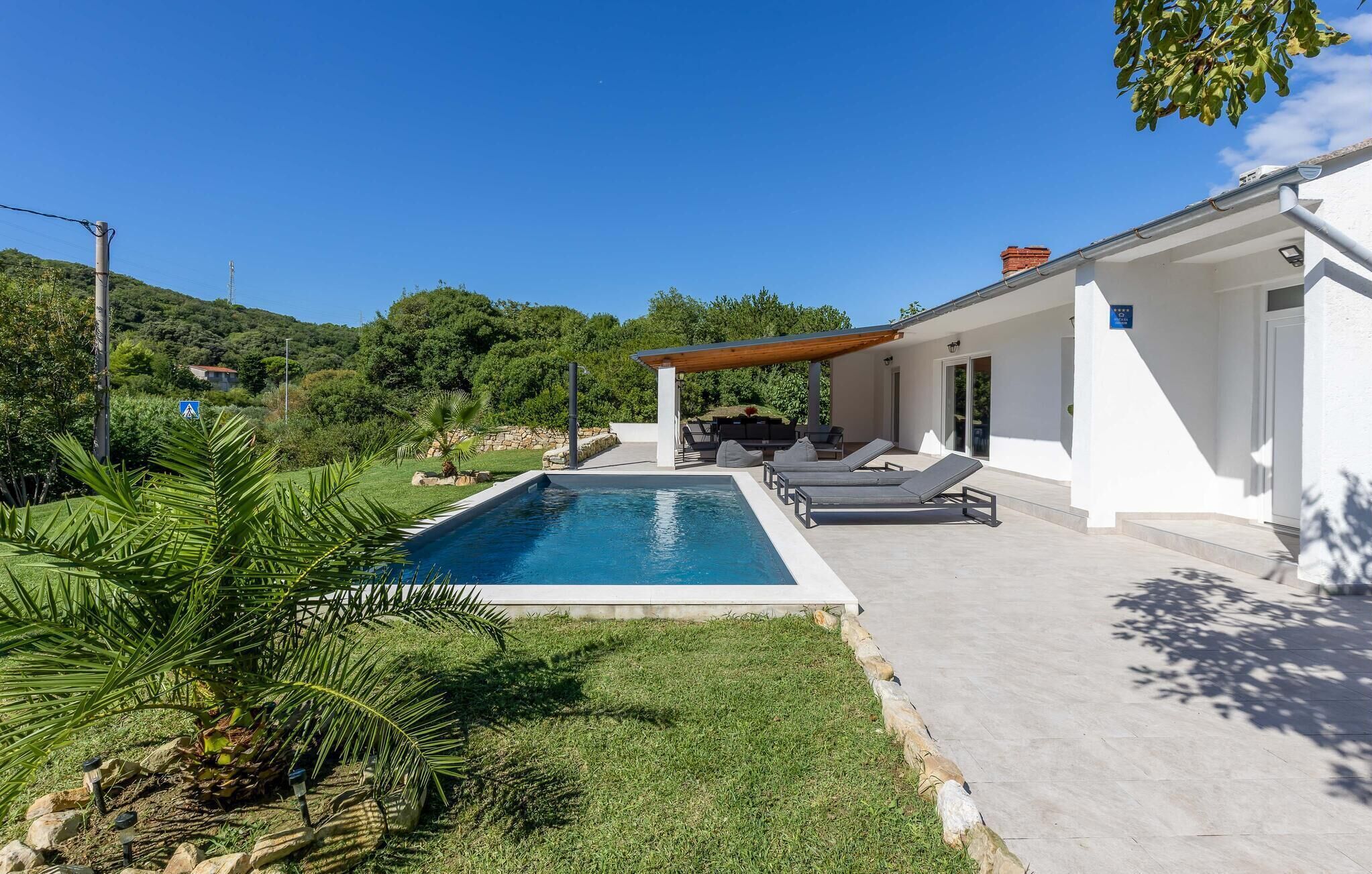 A modern house with a swimming pool, outdoor seating, and a view of the surrounding greenery.