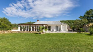 A modern house with a covered patio, a well-maintained lawn, and a mountainous backdrop.