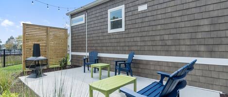 A patio area with outdoor furniture, a barbecue grill, and string lights against a house with siding.