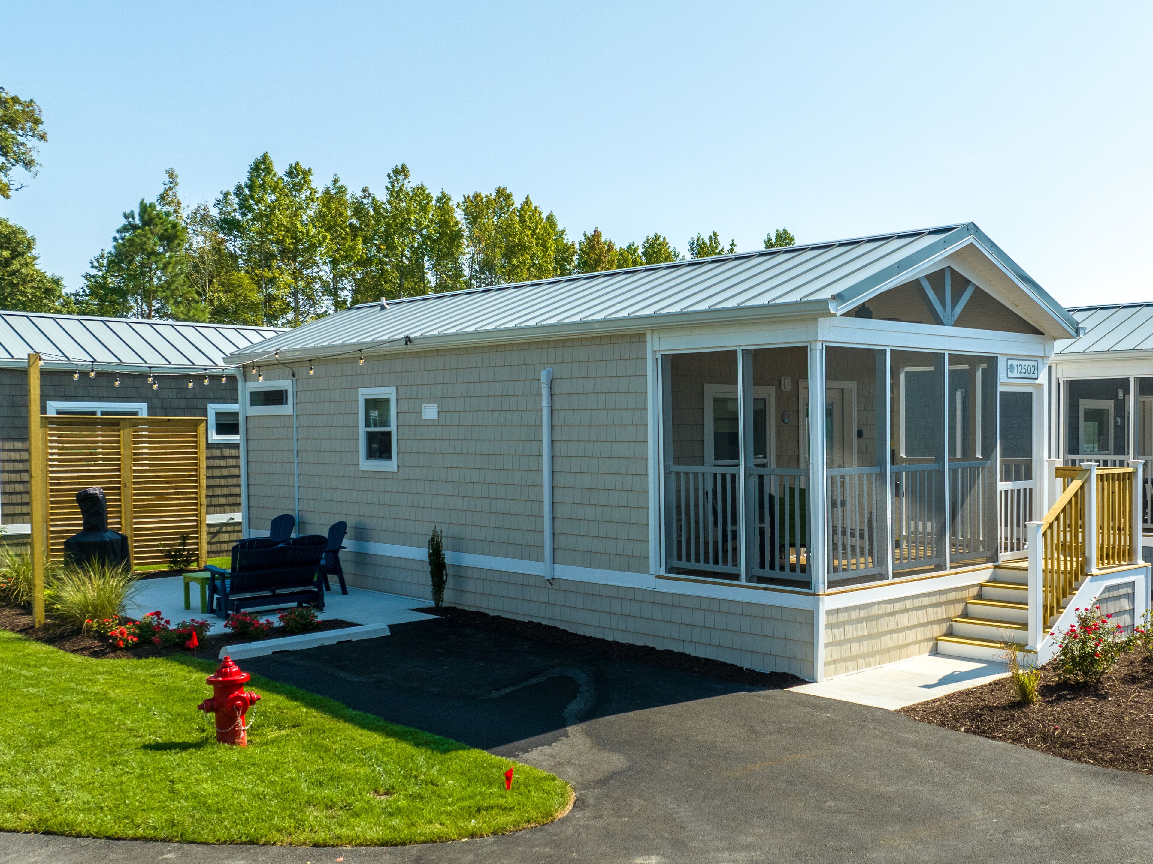 Een gelijkvloers huis met een overdekte veranda, een kleine voortuin en een buitenkraan.