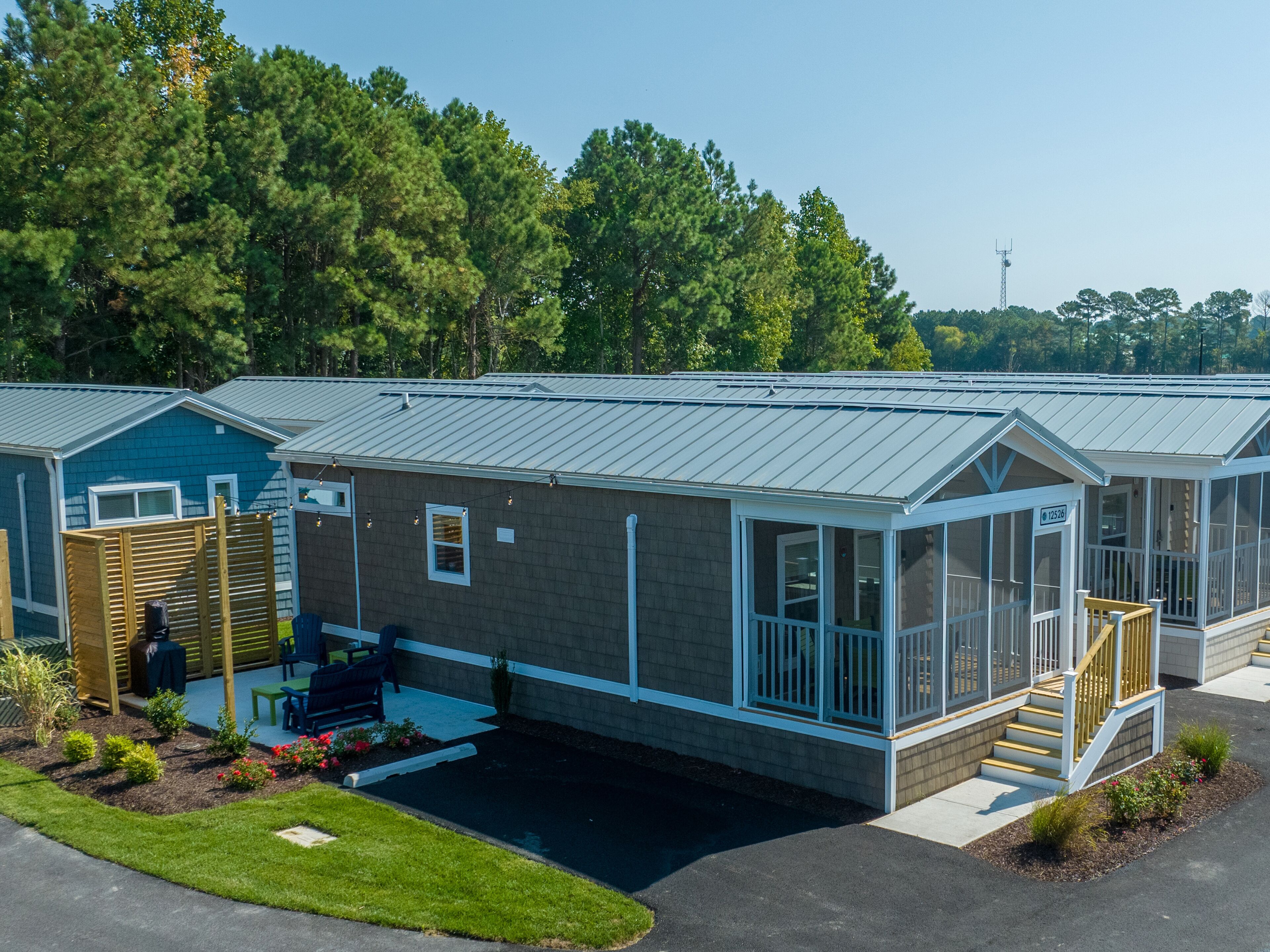 A row of mobile homes with attached porches, a covered parking area, and a landscaped garden.