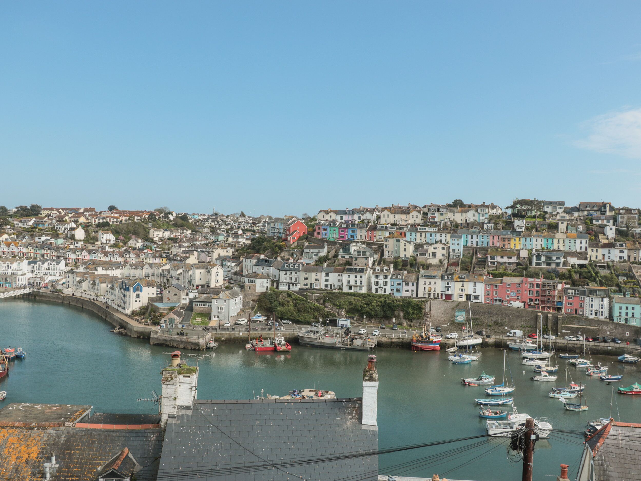 A coastal town with colorful buildings, a harbor with boats, and a clear sky.