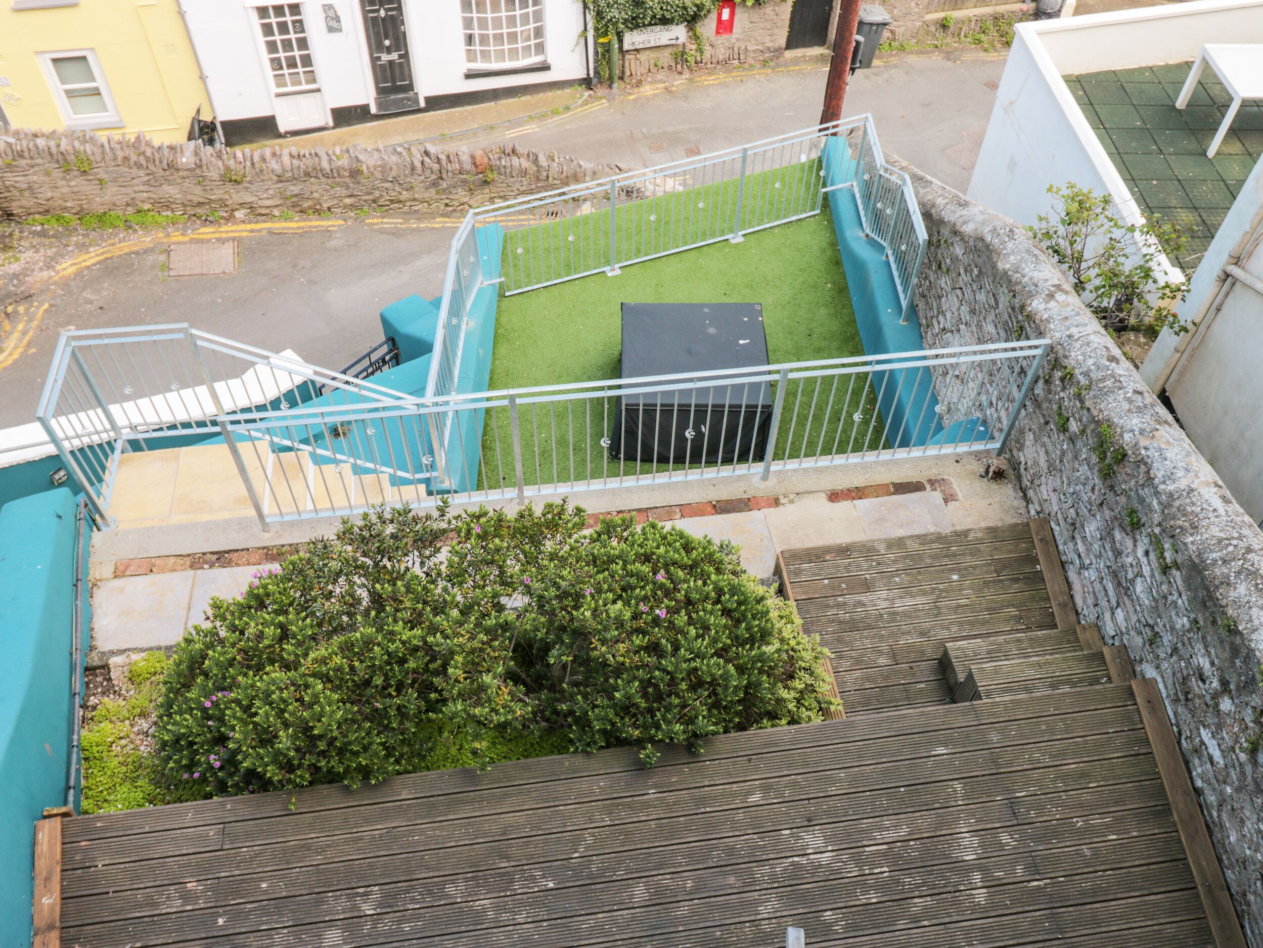 Eine Treppe führt zu einem Balkon mit Blick auf die Straße, eine kleine Rasenfläche und ein Holzterrasse.