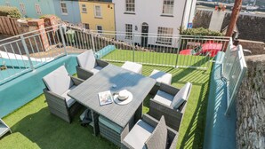 A rooftop terrace with a table and chairs, surrounded by a white fence, overlooking a residential area with colorful houses. - 2 North Furzeham Road (Brixham)