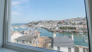 A coastal town with a marina, buildings, and a clear sky. - 2 North Furzeham Road (Brixham)