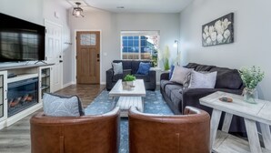 A modern living room with a fireplace, a large TV, and a comfortable seating area with a couch and chairs.