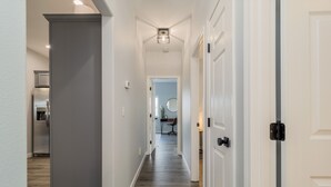 A hallway with a wooden floor, white walls, and a ceiling light fixture.