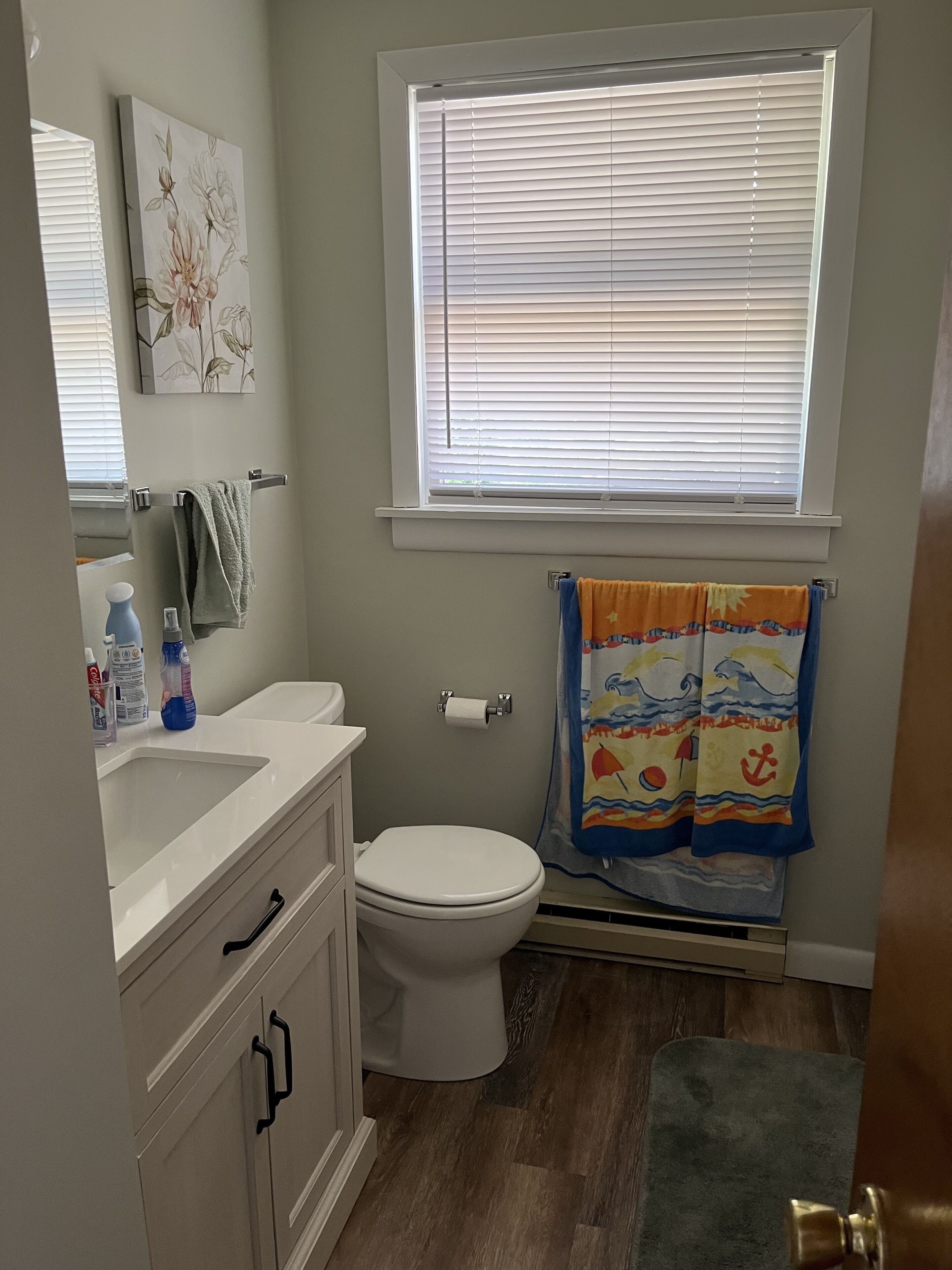 Baño con inodoro, lavamanos y ventana con persianas.