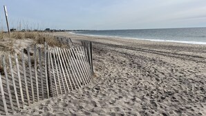 A sandy beach with a wooden fence and a clear view of the ocean. - Peaceful 3-Bedroom Beach Cottage with Deck, Beach Parking Pass & Outdoor Shower (South Kingstown)