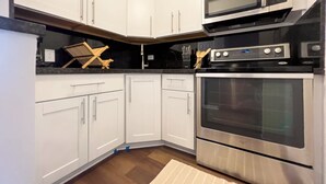Une cuisine moderne avec des meubles blancs, un four à micro-ondes, un four traditionnel et un plan de travail noir.