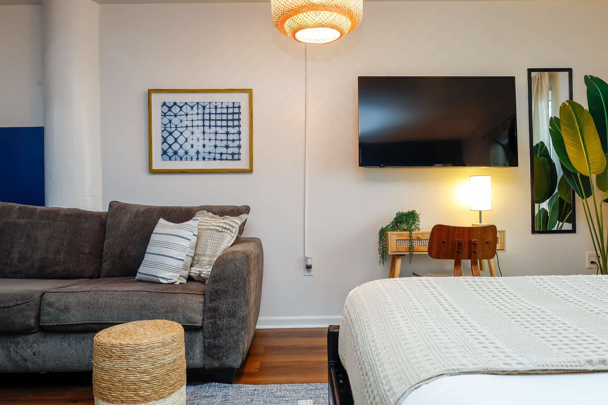Un salon moderne avec un canapé, un téléviseur à écran plat, une lampe et une œuvre d’art encadrée.
