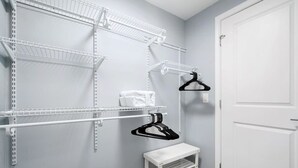 A closet with white shelving units, a white bench, and a door. - Newly Renovated 1 Bedroom (Columbus)