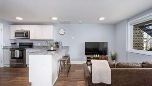 A modern kitchen with white cabinets, a central island, and a built-in microwave.