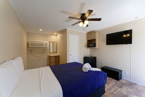 A bedroom with a bed, ceiling fan, TV, and built-in storage.