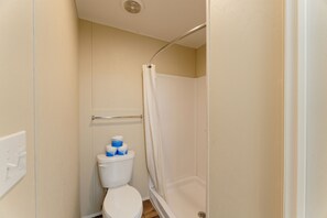 A small, enclosed bathroom with a toilet, a shower stall, and a towel rack.