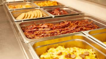 A buffet with various food options including bacon, eggs, and other breakfast items.