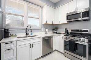 A modern kitchen with white cabinets, stainless steel appliances, a dishwasher, and a microwave. - Beautiful 1 Bedroom in the Heart of Short North (Columbus)