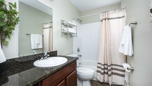 Une salle de bain équipée d’un lavabo, d’un miroir, d’un porte-serviettes et d’un rideau de douche.