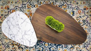 Dos mesas redondas con distintas superficies: una con diseño de mármol y la otra con acabado de madera, sobre una alfombra estampada.