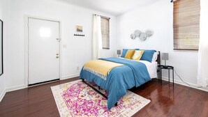 Un dormitorio con una cama, una mesita de noche, una lámpara y una puerta.