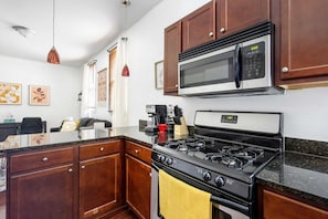 A kitchen with wooden cabinets, a stainless steel microwave, a gas stove, and a coffee maker.