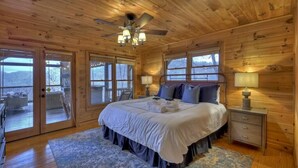A wooden cabin bedroom with a bed, nightstands, and a ceiling fan. - Sharin-A-Lakeview | $229 Off Your Stay! (Blue Ridge)