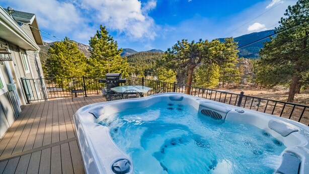 Un bain à remous sur une terrasse en bois, avec une vue sur les montagnes en arrière-plan.