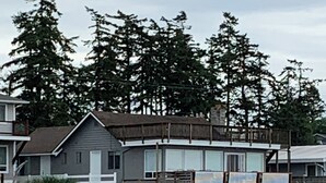 A waterfront property with a small house, a wooden deck, and a dock extending into a body of water. - Hop off the steps onto the beach - a rare Birch Bay Find!  Kayaks, full kitchen. (Blaine)