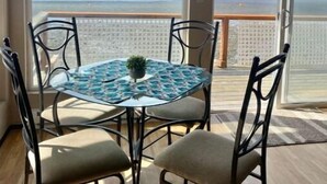 A dining area with a glass table and chairs, a small plant, and a view of the sea through large sliding doors. - Hop off the steps onto the beach - a rare Birch Bay Find!  Kayaks, full kitchen. (Blaine)