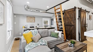 Una sala de estar moderna con un sofá modular gris, una mesa de centro de madera y una escalera que conduce a una zona superior.