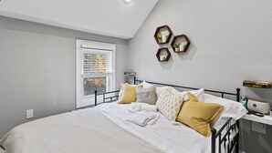 Un dormitorio con cama, mesita de noche y ventana.